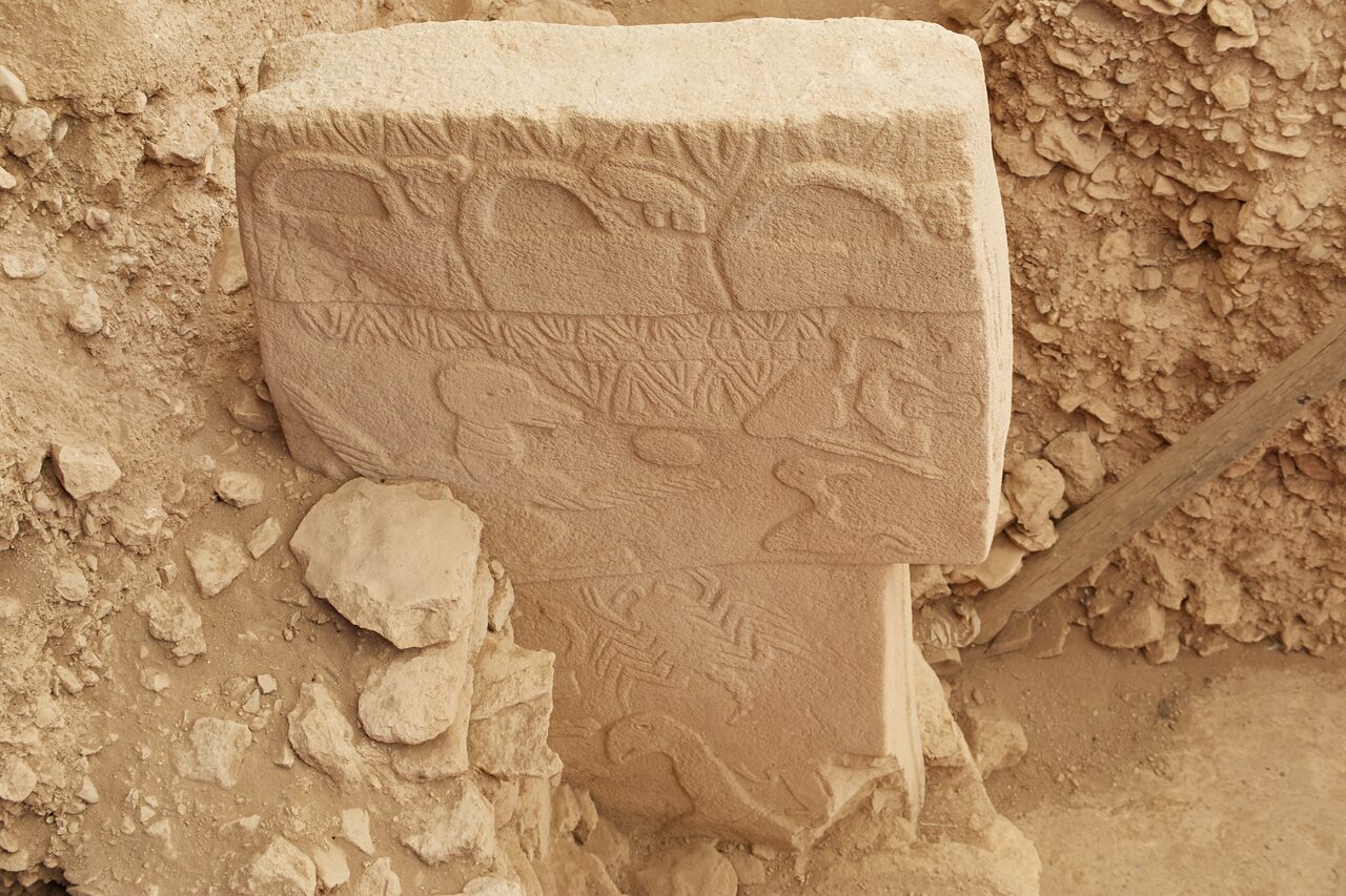 Pillar 43, the Vulture Stone: three ‘handbag’ motifs along the top edge, the vulture balancing a disc, and a scorpion below