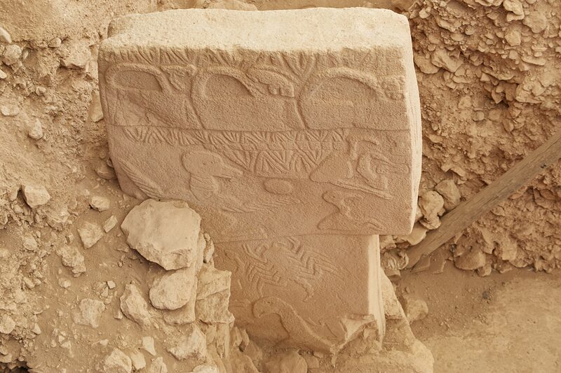 Pillar 43, the Vulture Stone: three ‘handbag’ motifs along the top edge, the vulture balancing a disc, and a scorpion below