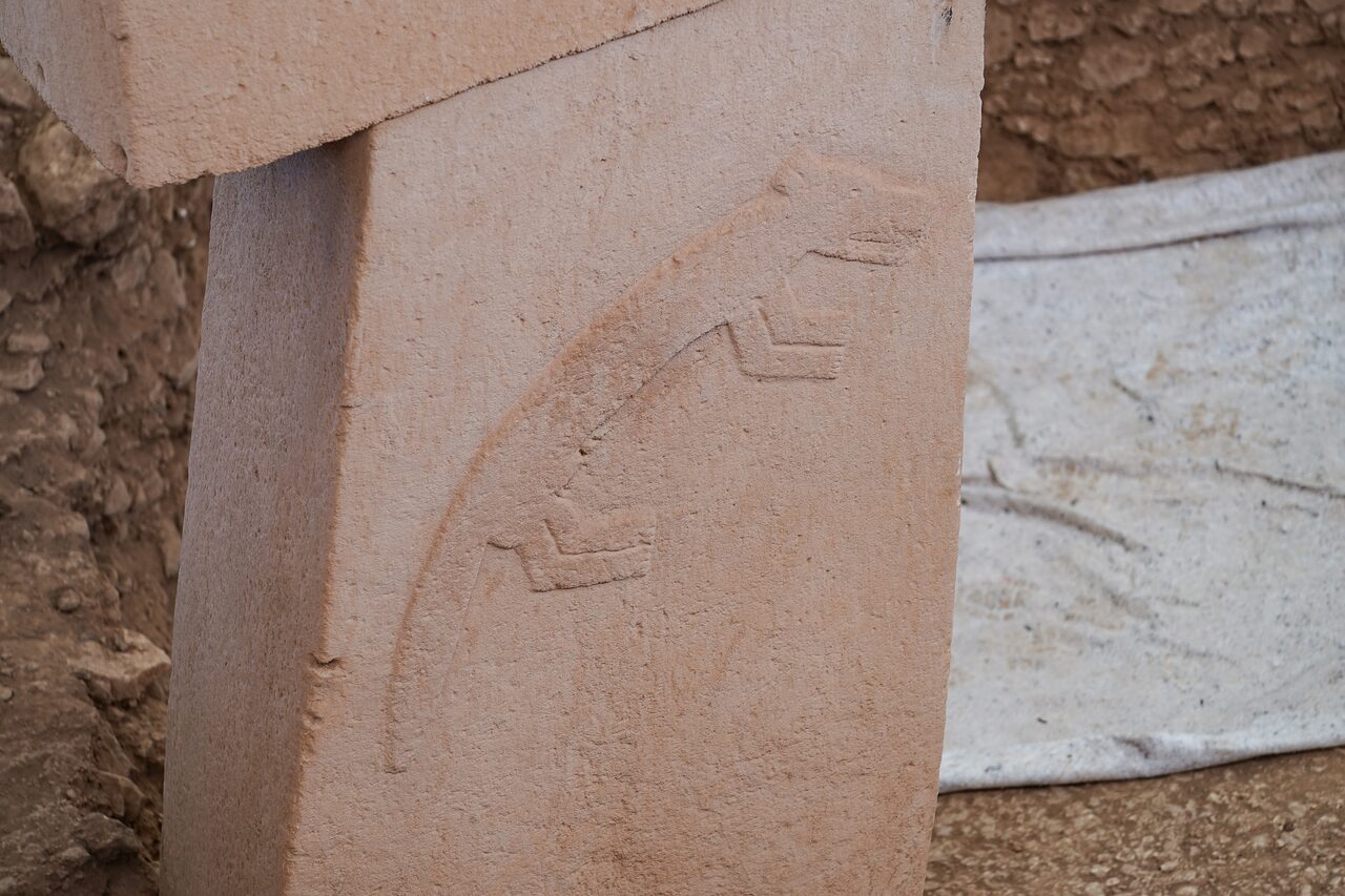 A carved arm bending at the elbow on the side of a central pillar